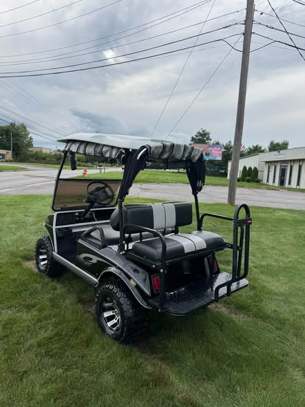 rear view of black Club Car DS electric cart on all-terrain tires
