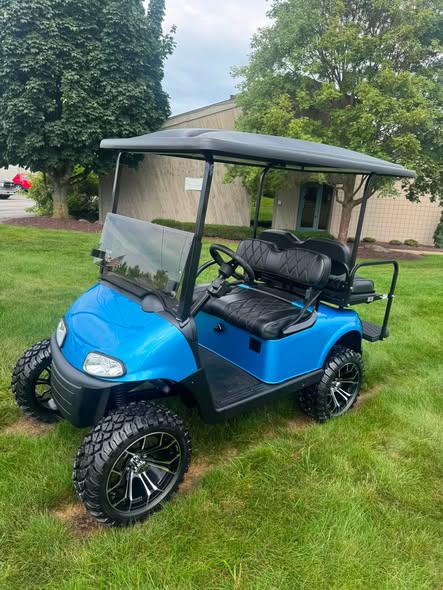 blue EZGO RXV EFI golf cart lifted with black seats on grass
