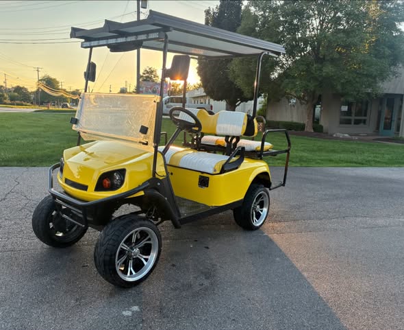 yellow-ezgo-express-s4-golf-cart-1 yellow EZGO Express S4 golf cart lifted with polished wheels at sunset
